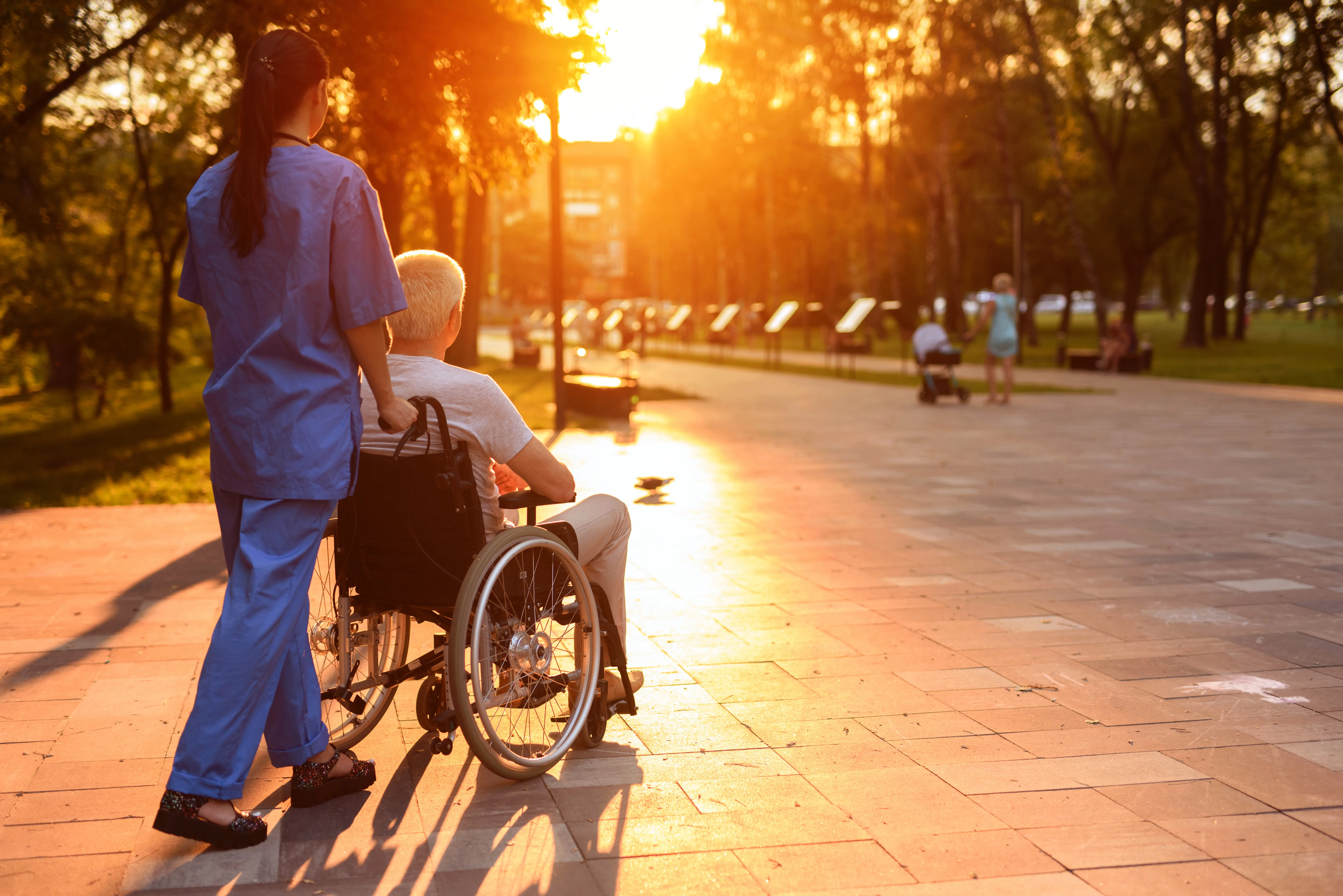 A caregiver helping an elderly man use a walker